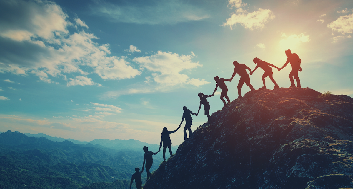 Climbers helping each other up a mountain